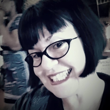 Woman with black frame glasses and shirt black hair smiling