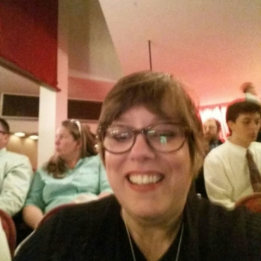 Woman with glasses smiling with people behind her