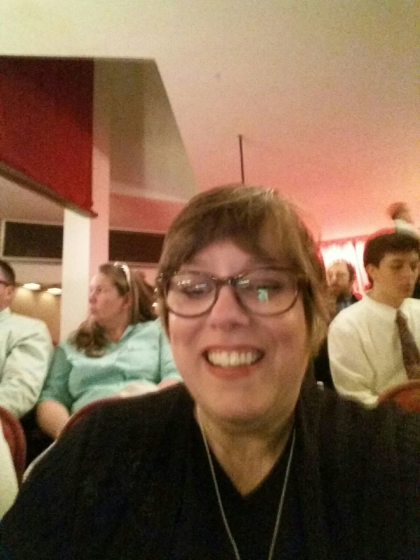 Woman with glasses smiling with people behind her