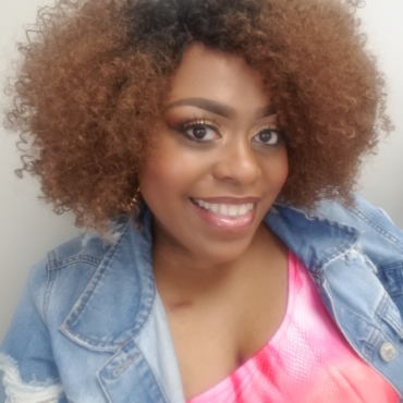 Woman smiling in a selfie with jean jacket and pink shirt