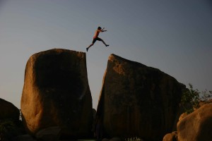 Person leaping between two rocks