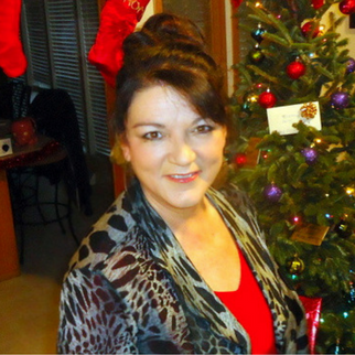 Woman in red shirt and blazer in front of a Christmas tree