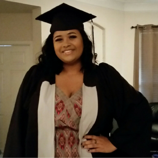 Woman in graduation gown smiling with hand on hip