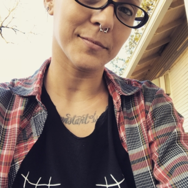 Woman with black glasses and nose piercing and flannel