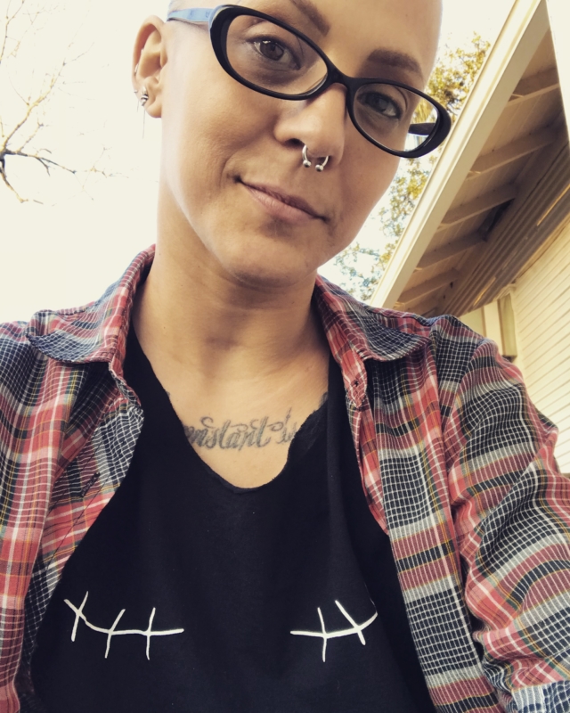 Woman with black glasses and nose piercing and flannel