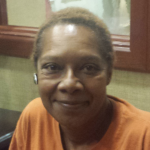 Lady in burnt orange shirt smiling at camera