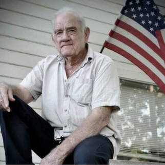 Man in button up shirt with American flag behind him