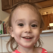 Younger female child smiling at camera in a kitchen