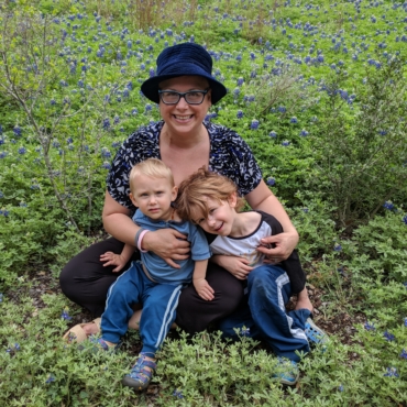 Woman and two boys in blue sitting in a bluebonnet field