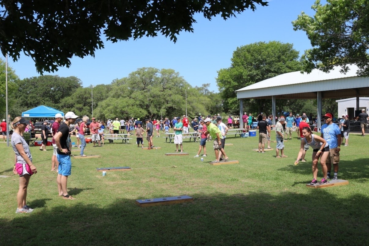 Community outdoor event with several people bean bag tossing