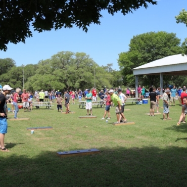 Community outdoor event with several people bean bag tossing