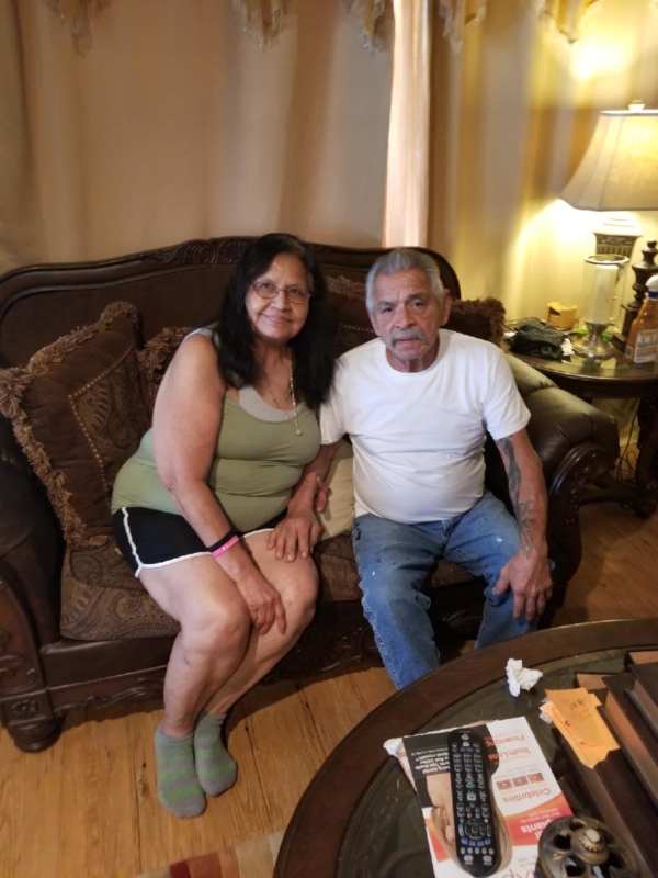 Woman in green with man in white shirt sitting on couch