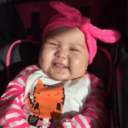 Baby in striped pink shirt and pink-tied bow smiling