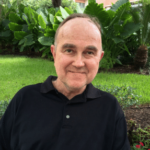 Man in black collared shirt smiling outdoors