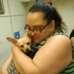 Woman in green striped shirt and glasses with dog