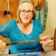 Woman in glasses and teal shirt looking at camera