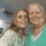 Lady in white shirt with woman in teal shirt smiling at the camera under a fan