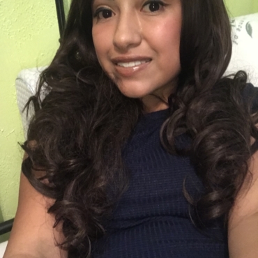 Young woman with brown curly hair and navy shirt, smiling