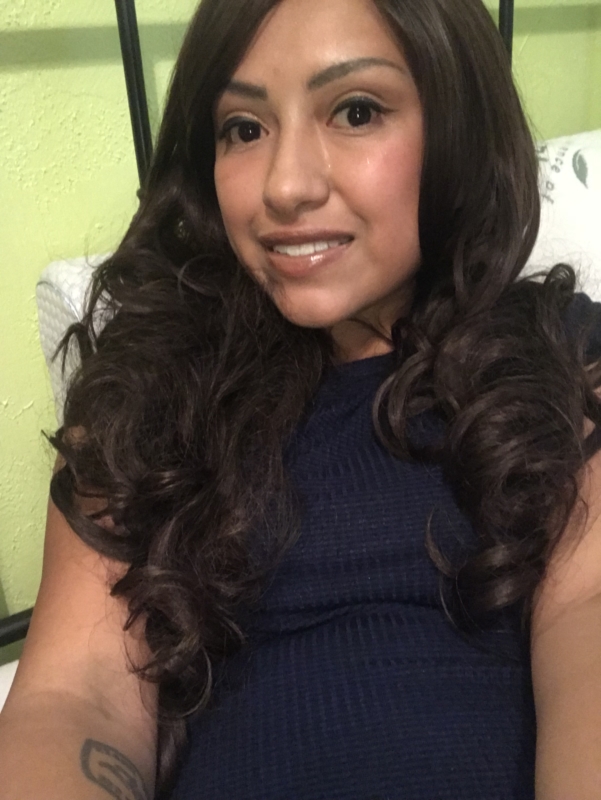 Young woman with brown curly hair and navy shirt, smiling