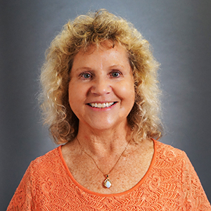 Woman with necklace and orange shirt smiling