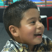 Side angle of boy smiling in yellow plaid shirt