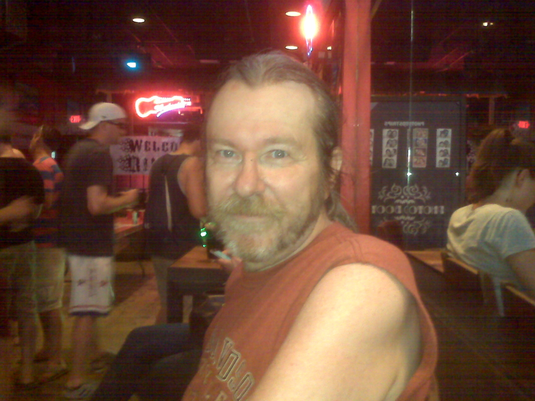 Man in orange tank top at a bar