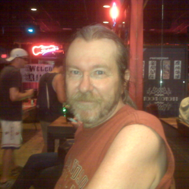 Man in orange tank top at a bar