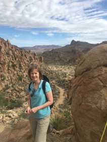 Woman in teal shirt and khakis hiking with backpack