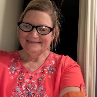 Woman in red flowery shirt and black-framed glasses smiling