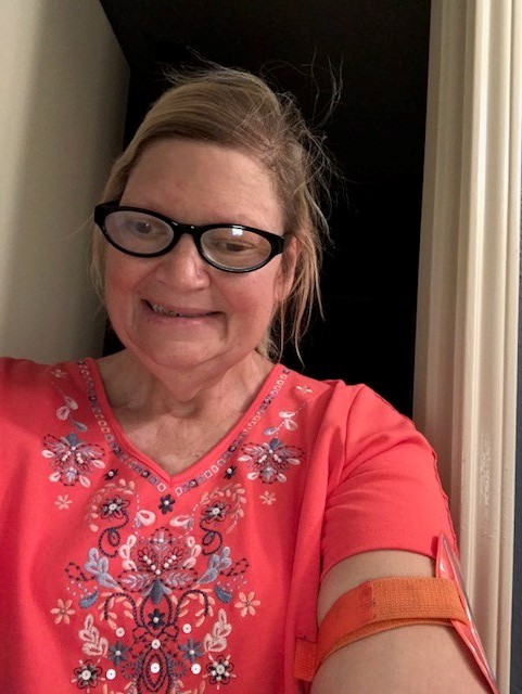 Woman in red flowery shirt and black-framed glasses smiling