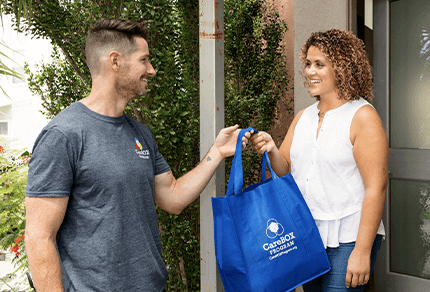 A man handing a woman a carebox at her doorstep